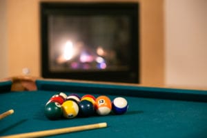 The Recovery House pool table with a fireplace in the background